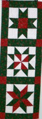 Red green $ white Christmas prints in 3 different star patterns give this table runner more interest. Machine pieced and machine quilted by Linda Monasky.<br />