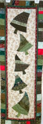 Swaying trees table runner. Strip pieced and machine quilted trees on a neutral background, topped off by a machine pieced border give this whimsical table runner charm.Machine appliqued by Laurel, machine quited by Linda Monasky <br />  